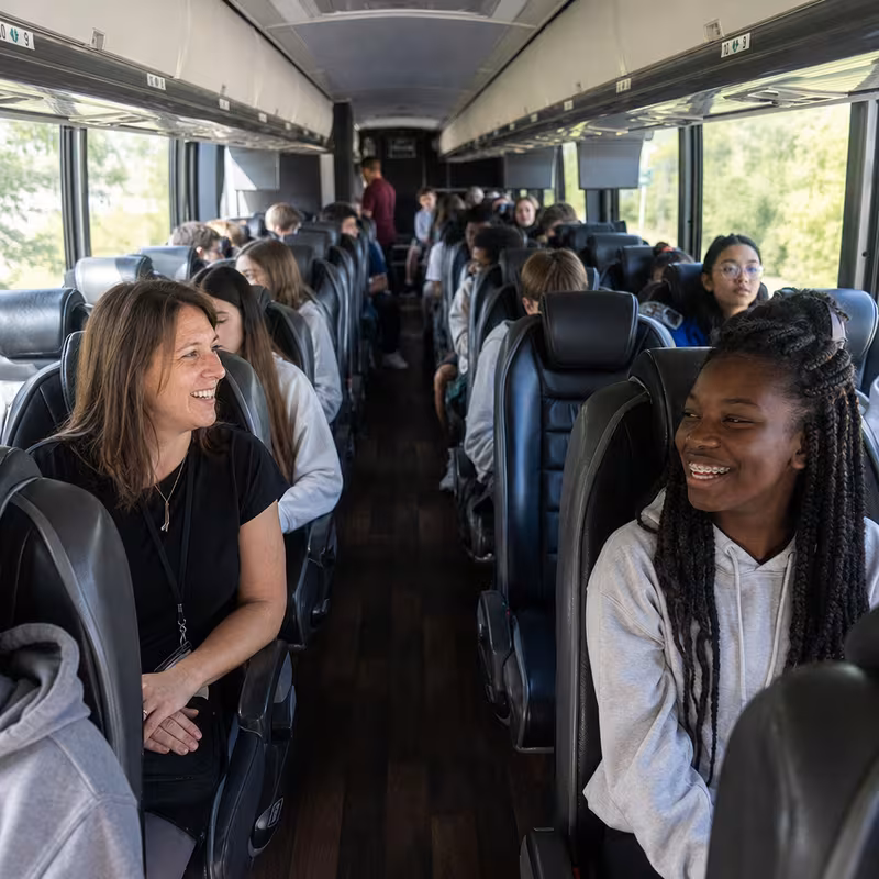 Group boarding a white charter bus for School Transportation transportation in Tucson